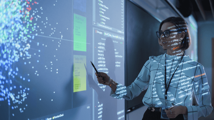 female professor pointing to white board with digital overlay projected onto her