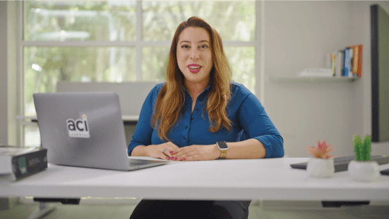 happy woman sitting at desk with ayy see eye computer