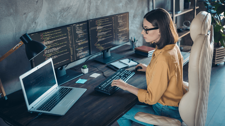 woman in front of laptop and monitors working